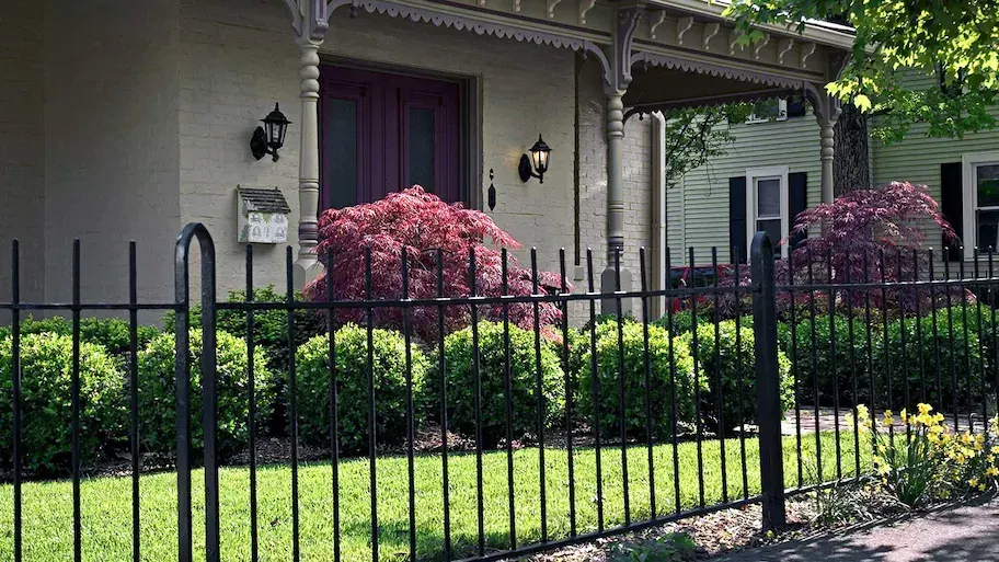 Black iron fence in front of a brick home with landscaping